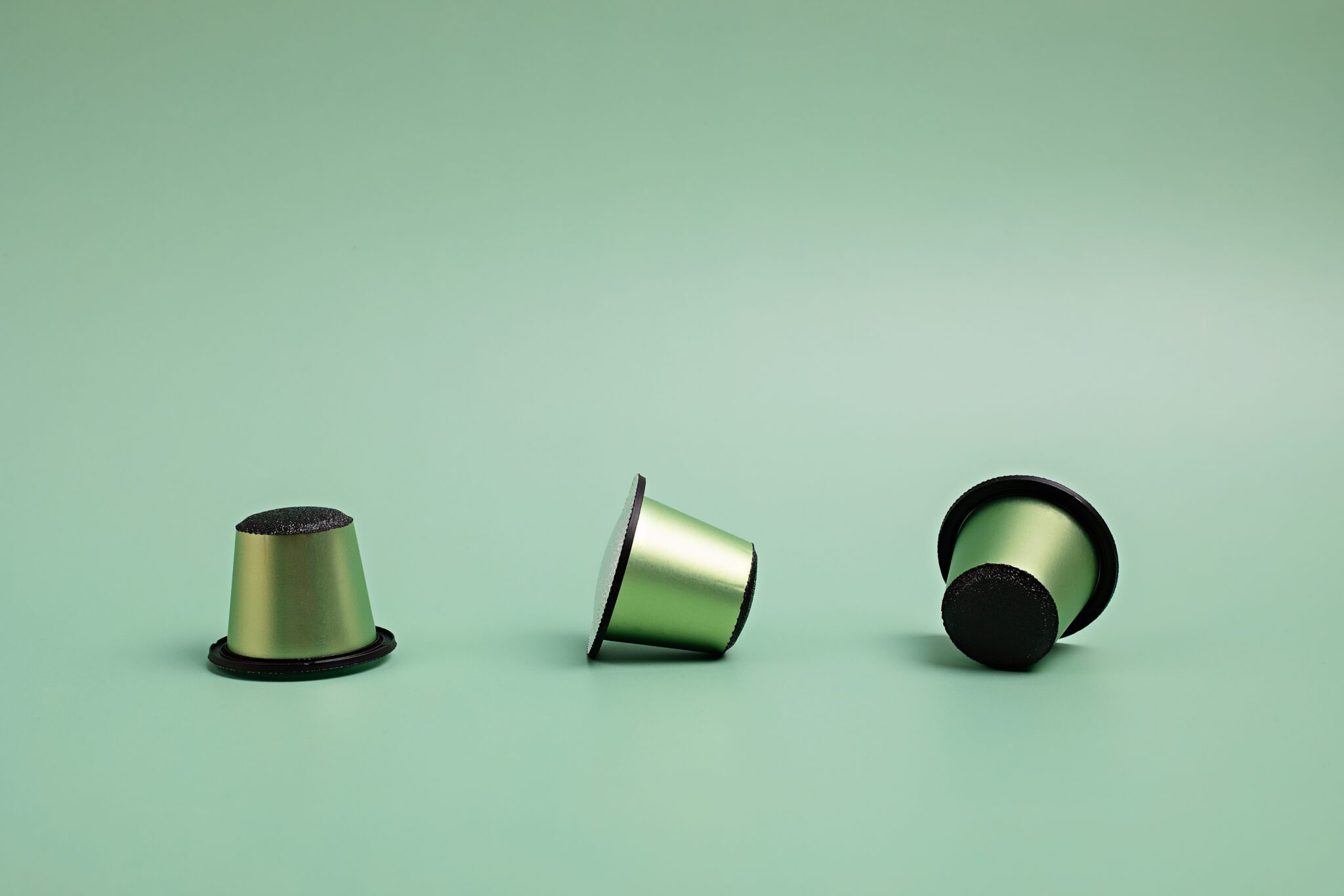 Disposable coffee capsules over green background with copy space. Morning dose of caffeine, energy