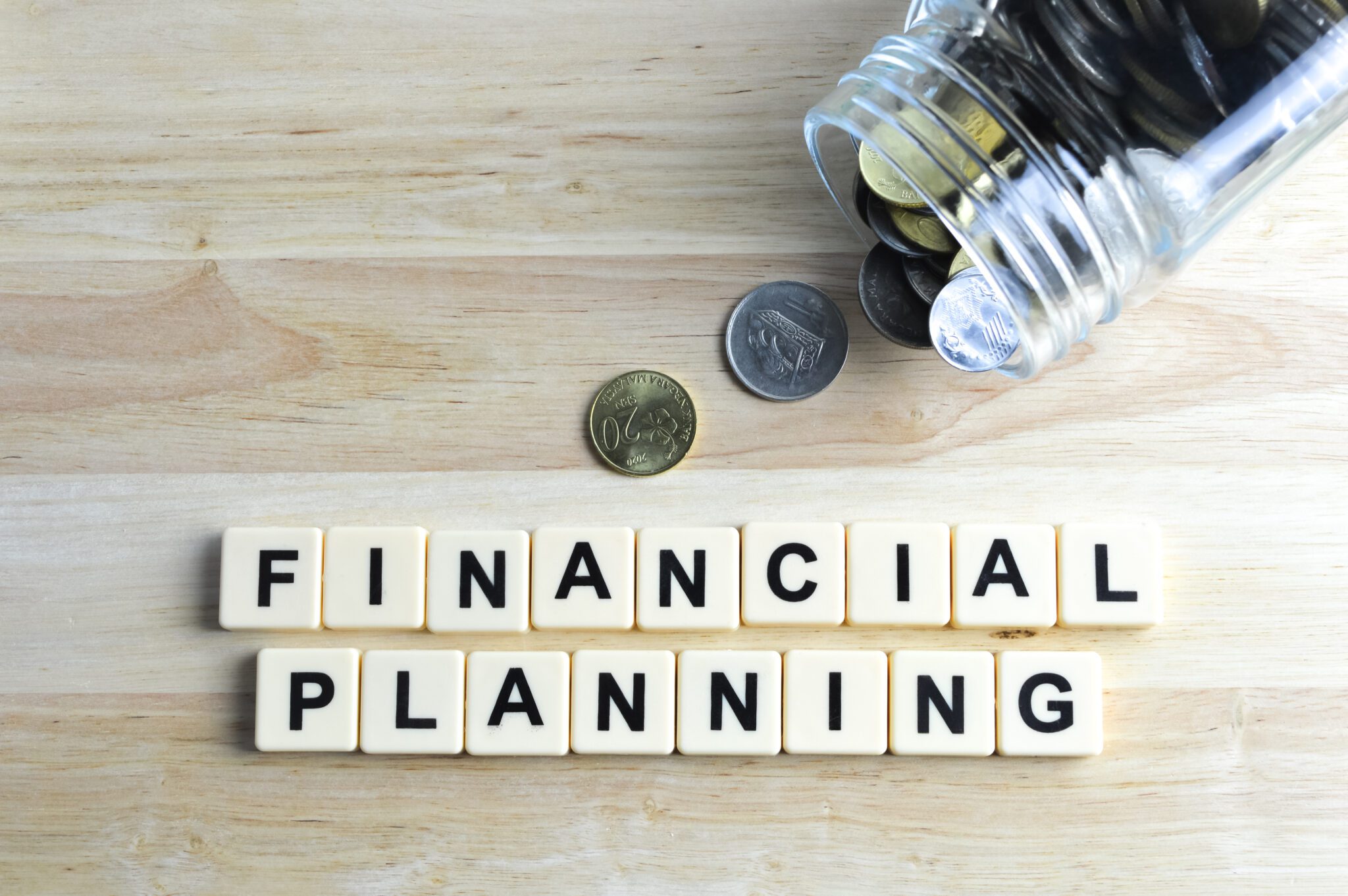 Stack of coins and scrabble letters with text FINANCIAL PLANNING.